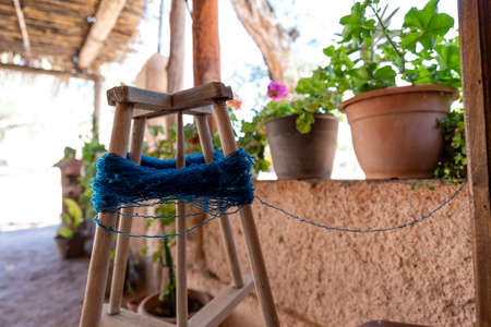 blue yarn for knitting handmade ponchos wound on wooden spool - flowers in backgroundの写真素材