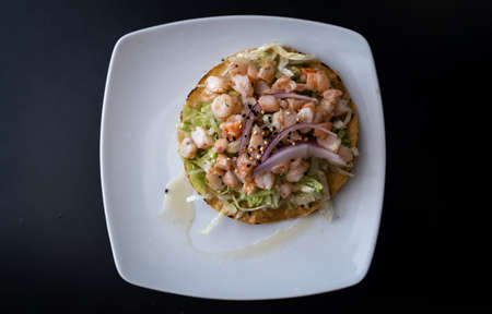 photo from above of a Mexican tortilla with shrimp and vegetables on a white plate and black background - typical Mexican foodの写真素材