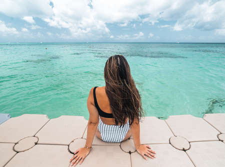 hispanic woman sitting on her back facing the caribbean sea in Cozumel Mexicoの写真素材