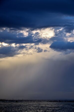 Deep blue rainclouds over rough seaの写真素材
