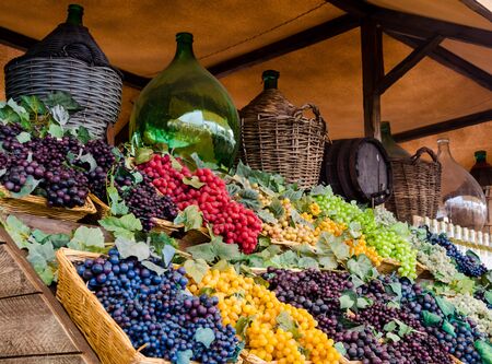 Variety of grapes and wine jugs displayed on a market stallの写真素材