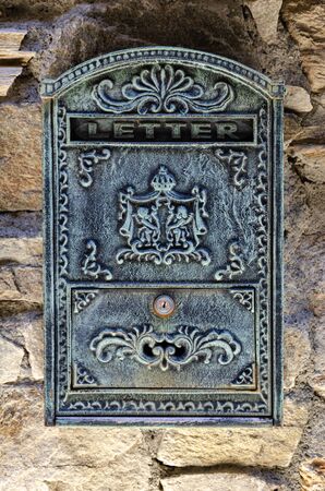 Metal mailbox with engravings on a stone wall backgroundの写真素材