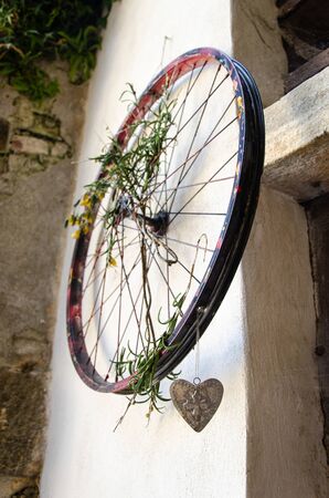 Old bike wheel with grass and metal heart hangingの写真素材