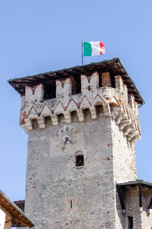 Medieval clock tower with waving Italian flag on blue sky backgroundの写真素材