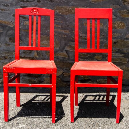 Vintage wooden red chair outside a house with brick wall in the sunの写真素材