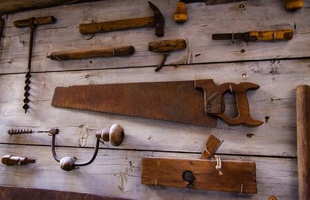 Collection of old rusty tools pinned on a wooden boardの写真素材