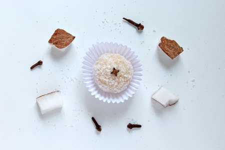 Sweet made from coconut, called "Beijinho" on white background with ingredients: coconut, cloves and sugarの写真素材