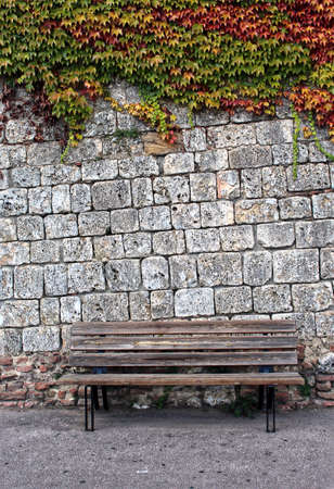Wooden bench with flowered brick wall background. Background with space for text.の写真素材