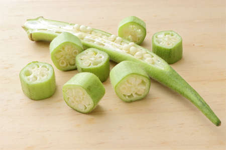 Raw green okra sliced â€‹â€‹on wooden table