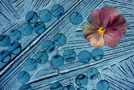 A blue abstract with a pink flower in the upper right cornerの写真素材