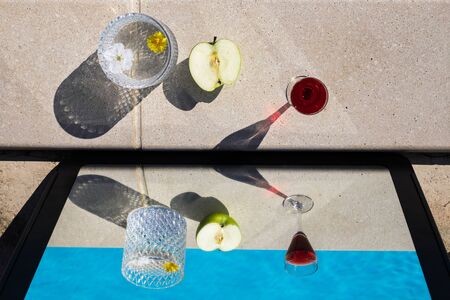 two glasses and an apple next to the pool with the mirror effectの写真素材