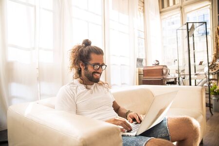 man with long hair working with his laptop in a officeの写真素材