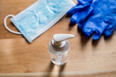hands dispenser with a mask and medical blue gloves on a wooden backgroundの写真素材