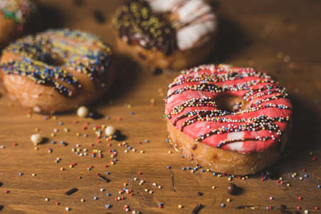 colorful donuts on a wooden table with some candies