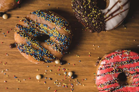 colorful donuts on a wooden table with some candies
