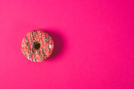 close up of a pink donut on a pink backgroundの写真素材