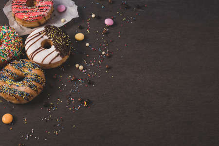 colorful donuts with some candies on a black tableの写真素材