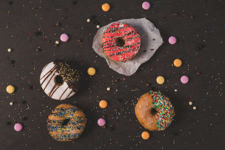 colorful donuts with some candies on a black tableの写真素材