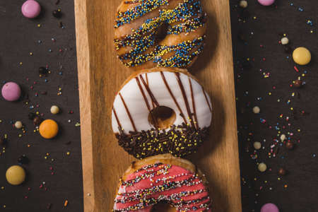 colorful donuts on a wooden table with a black backgroundの写真素材