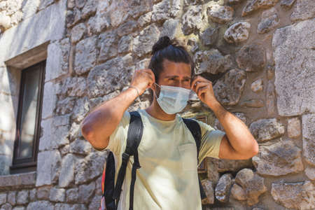 young man walking in a village wearing a face pollution mask to protect himself from the coronavirus