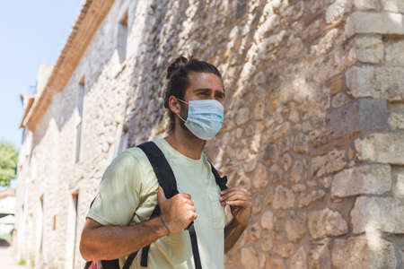 young man walking in a village wearing a face pollution mask to protect himself from the coronavirus