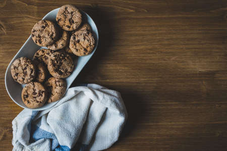 some chocolate cookies with a plate and a napkin on a wooden background