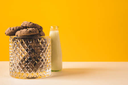 chocolate chip cookies with a bottle of milk on a yellow backgroundの写真素材