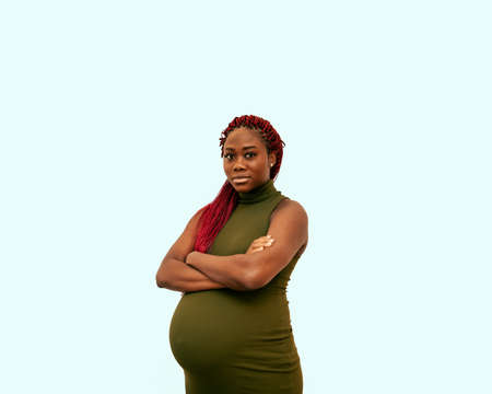 black pregnan woman wearing a green dress on a colorful backgroundの写真素材