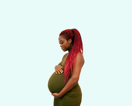 black pregnan woman wearing a green dress on a colorful backgroundの写真素材