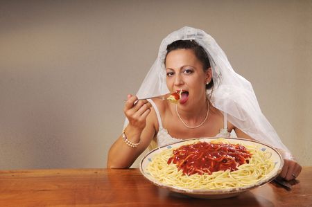young bride eats spaghetti with tomato in rustic settingの写真素材