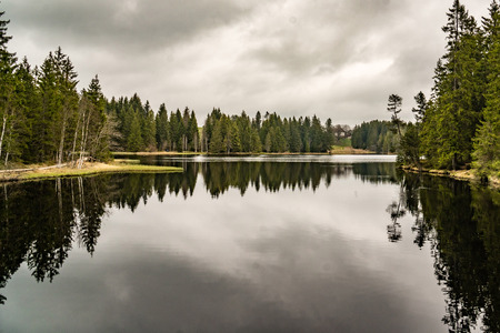 mystery lake with forest, dark water reflection cloudy