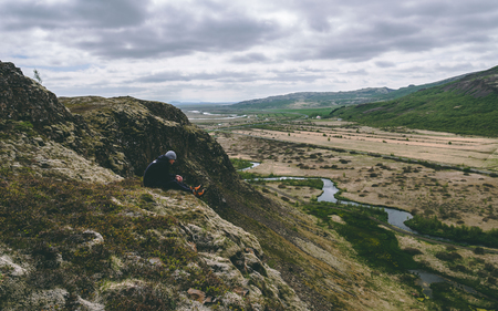 guy sitting on the edge of a cliff in iceland face not visibleの写真素材