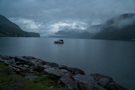little boat on a lake a mystery cloudy day in norway geirangerの写真素材