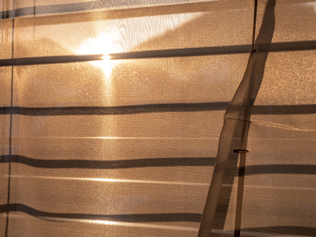 sun shining through roller blinds and curtain during golden hourの写真素材