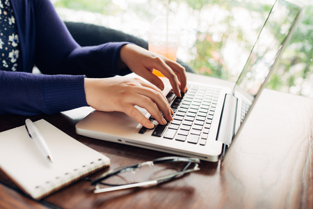 Woman hands working with a laptop in a coffee shopの写真素材