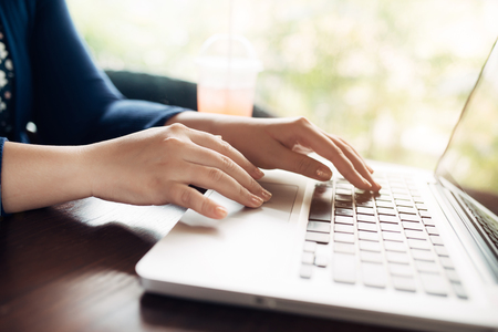Woman hands working with a laptop in a coffee shopの写真素材