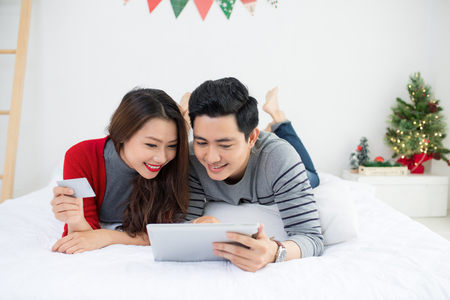 Christmas. Asian Couple Shopping Online at home celebrating New Year.の写真素材