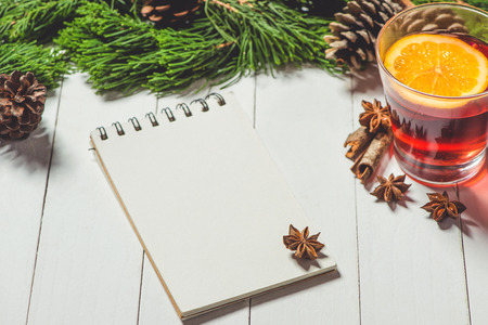 Christmas drink. Glass cup of tea with lemon and cinnamon with notebook on wood tableの写真素材