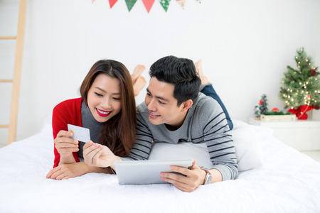 Christmas. Asian Couple Shopping Online at home celebrating New Year.の写真素材