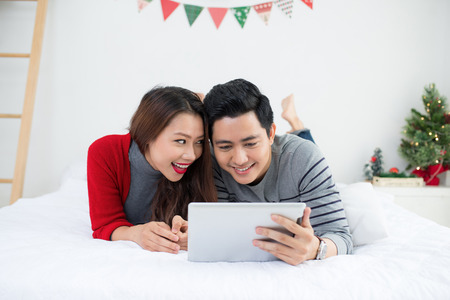 Christmas. Asian Couple using digital tablet at home celebrating New Year.の写真素材