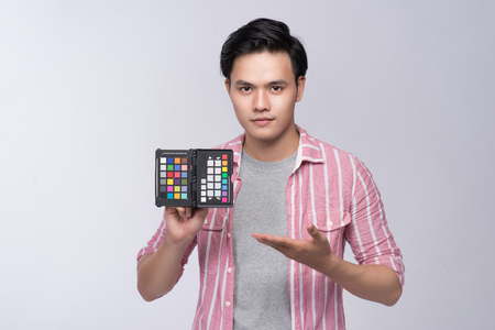 Young asian photographer holding color checker card, while working in studioの写真素材
