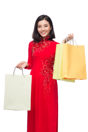 Charming Vietnamese Woman in Red Ao Dai Traditional Dress holding Shopping Bags.の写真素材