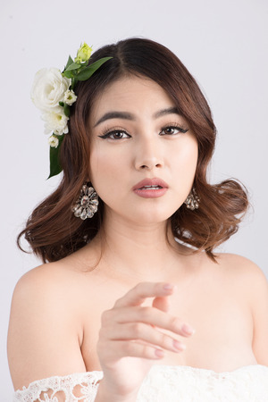 Beautiful asian woman bride on grey background. Closeup portraits with a professional makeupの写真素材