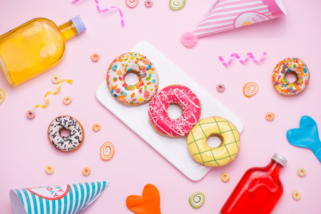 Party. Different colourful sugary round glazed donuts and bottles of drinks on pink background.の写真素材