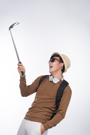 Happy young asian man taking self portrait photography through smart phoneの写真素材