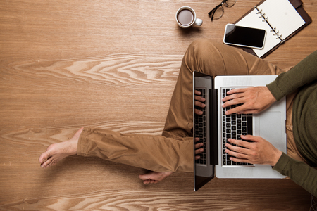 Business man hands using a laptop with a cup of coffee and smart phone with copy space.の写真素材