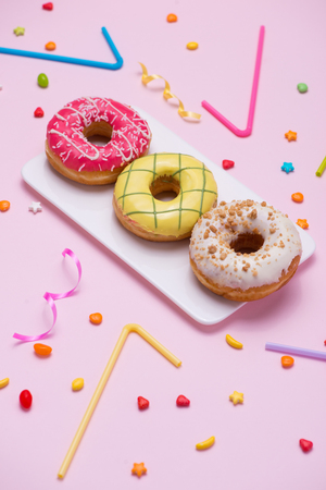 Party. Different colourful sugary round glazed donuts and bottles of drinks on pink background.の写真素材