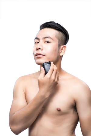 Young asian man shaving over white background and looking at cameraの写真素材