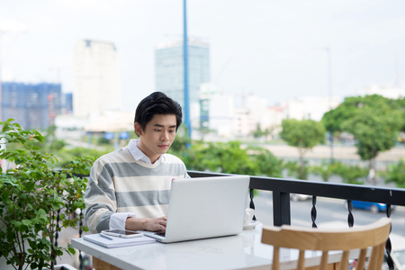 Asian young business man working with laptop at the city cafe.の写真素材
