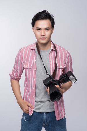 Young asian photographer holding digital camera, while working in studioの写真素材